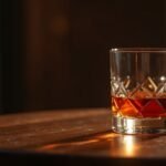 Egy pohár konyak egy fa asztalon, meleg fényben.