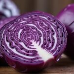 Szeletelt lilakáposzta friss levéllel a fából készült asztalon.