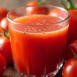 Friss paradicsomlé és érett paradicsomok a háttérben.