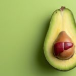 Avokádó fél, vörös máj formával a belsejében, zöld háttérrel.