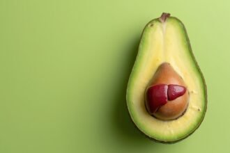 Avokádó fél, vörös máj formával a belsejében, zöld háttérrel.