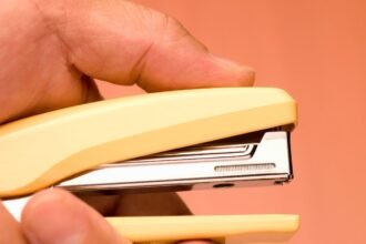 Sárga irodai tűzőgép kézben, tavaszi munkahelyi frissítéshez.