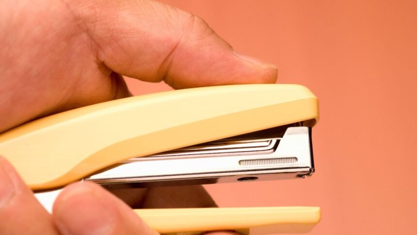 Sárga irodai tűzőgép kézben, tavaszi munkahelyi frissítéshez.