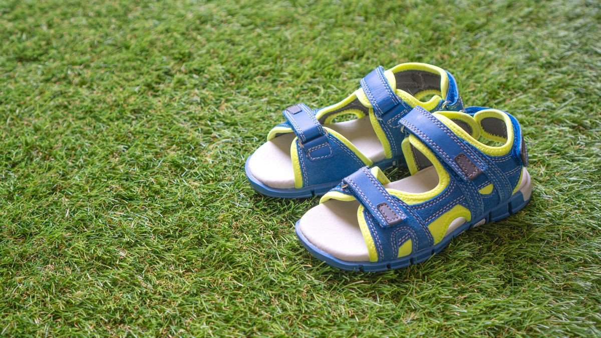 Kék és sárga gyerek szandál fű háttér előtt