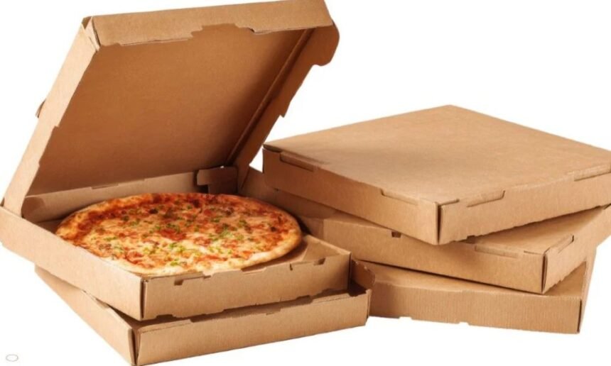Friss pizza klasszikus pizzadobozban, háttérben üres dobozok.
